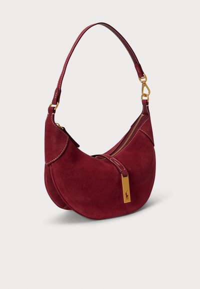 Τσάντα ώμου από μπουρντό σουέτ με καμπύλη σιλουέτα, χρυσά μεταλλικά στοιχεία, κλείσιμο με φερμουάρ και ραφές διακόσμησης. Διαθέτει έναν ρυθμιζόμενο ιμάντα.