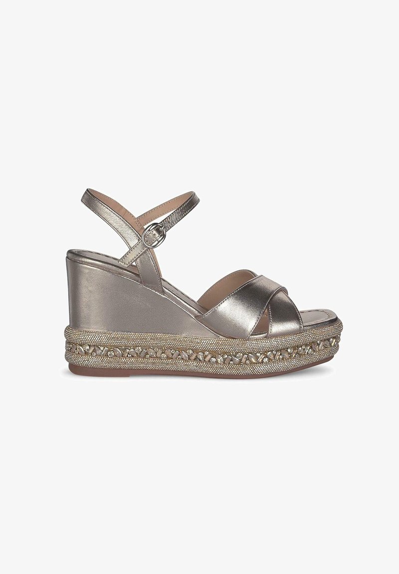 Metalen gouden wedge sandalen hebben crisscross banden en een gestructureerd plateau met geweven details en kleine decoratieve accenten.