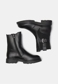 Black leather ankle boots with a side zipper, textured panels, and a decorative buckle. Features a chunky tread sole for grip.