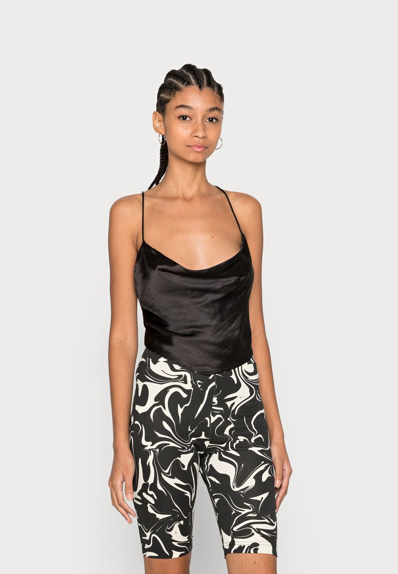 Camisola de cetim preta com alças finas combinada com calções de bicicleta de cintura alta com padrão marmoreado em preto e branco. Textura suave, design ajustado.