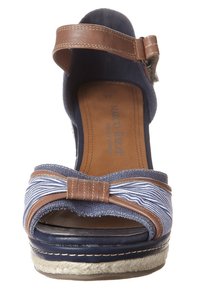 Námořnické modré espadrilové sandály na podpatku s pruhovanou látkovou mašlí a hnědými koženými akcenty; mají jutovou obuvní podešev a popruh kolem kotníku.