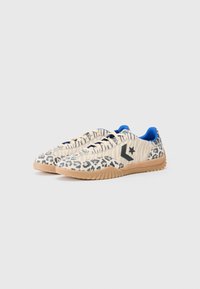 Sneakers i leopardprint med creme- og sorte striber, blå indre og karamelgummisål. Har et sort logo på siden.