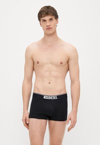 Melnu vīriešu bokseršorti ar baltu Diesel logotipu uz elastīgā vidukļa jostas, izgatavoti no mīksta, elastīga materiāla.