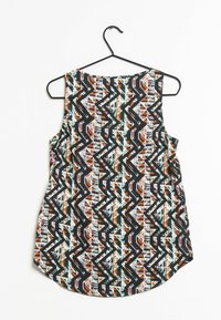 Top sin mangas con un patrón geométrico de zigzag y cuadrícula en negro, naranja, blanco y azul claro, colgado en una percha negra.