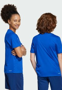 Kurzärmlige blaue Sporthemden aus atmungsaktivem Material, mit glatter Textur und Logodetail nahe dem Saum, kombiniert mit passenden Shorts.