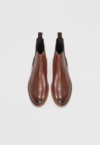 Botas de tornozelo em couro castanho com um acabamento suave, painéis laterais elásticos e puxadores. Ponta arredondada e detalhes cosidos na sola.