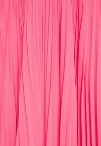 Tissu rose vif avec des plis verticaux espacés de manière régulière, créant une surface texturée et fluide.