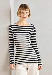 Långärmad randig topp i grått och marinblått, med en bred båthals och en figurnära silhuett. Tyget verkar mjukt och stretchigt.