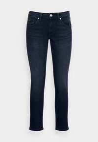 Tmavé džínsy s úzkým střihem, pětikapsovým designem a stř íbrnými detaily. Materiál má hladkou strukturu a mírný lesk.