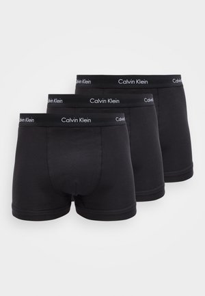 Drei Paar schwarze Calvin Klein Boxer-Briefs mit elastischem Bund und Markenlogo, auf einem weißen Hintergrund in versetzter Reihe angeordnet.