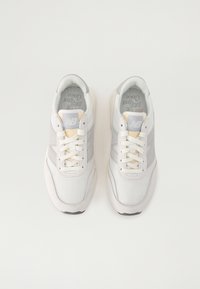 Grå och vita sneakers med mesh och mocka ovandel, texturerade detaljer, vita snören, vadderad krage och en kontrasterande logotyp på tungan.