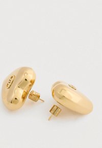 Pár leštěných náušnic ve zlatém tónu ve tvaru zaoblených, nepravidelných obláčků na světlém pozadí.