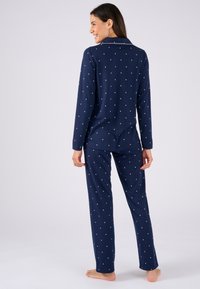 Ensemble de pyjama bleu marine en tissu doux, comprenant des manches longues, un pantalon droit et des détails à motifs d'étoiles blanches.