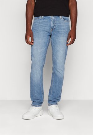 Lichtblauwe denim jeans met een recht gesneden ontwerp, vijf zakken en contrasterende stiksels, gecombineerd met witte sportschoenen.