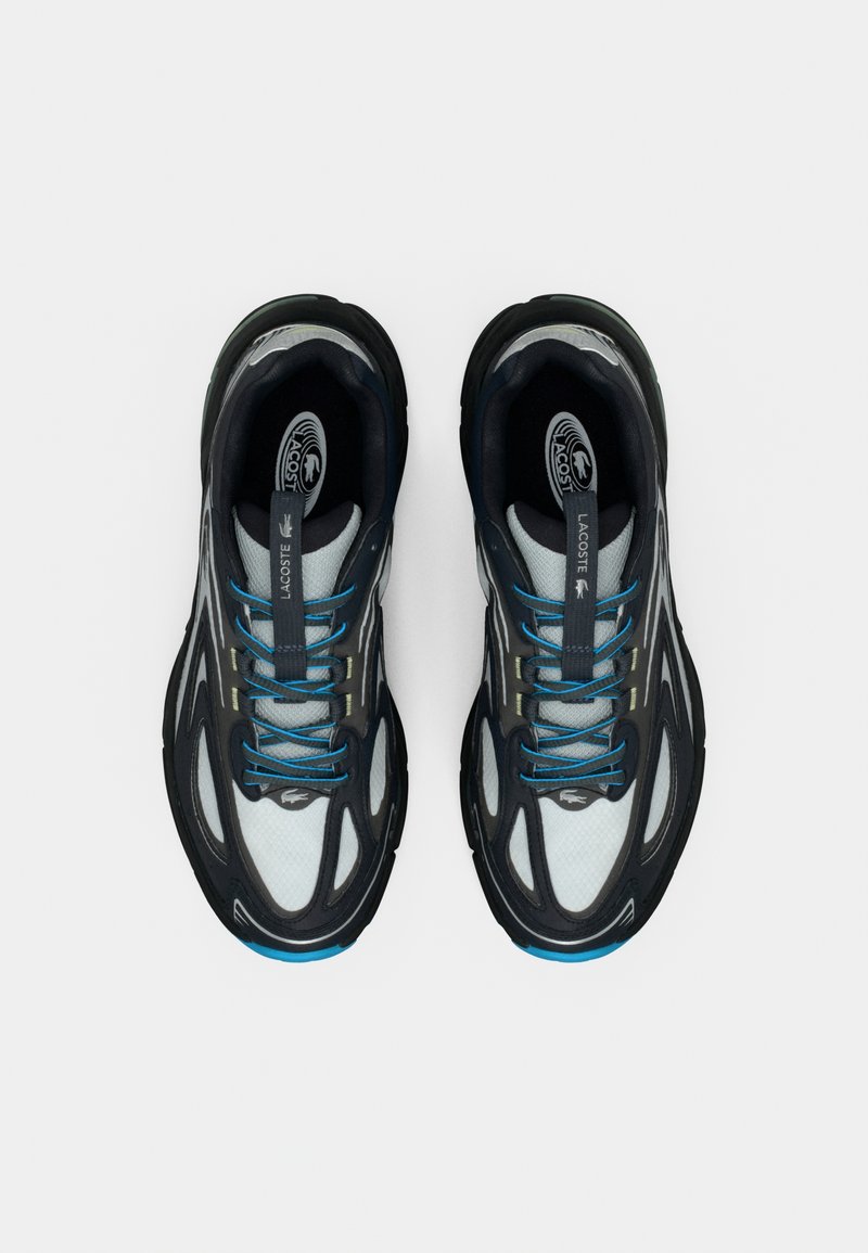 Chaussures de sport noires et grises avec une tige en mesh texturé, des lacets bleus, une semelle amortie, et un logo Lacoste sur la languette.