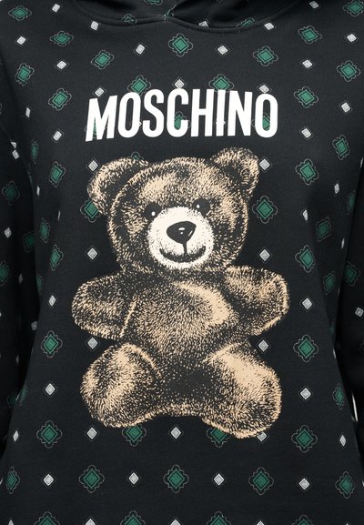 Μαύρο φούτερ με κουκούλα που διαθέτει μεγάλο σχέδιο με αρκουδάκι σε μπεζ χρώμα, περιτριγυρισμένο από ρόμβους σε πράσινο, λευκό και γκρι, με το κείμενο "Moschino" από πάνω.