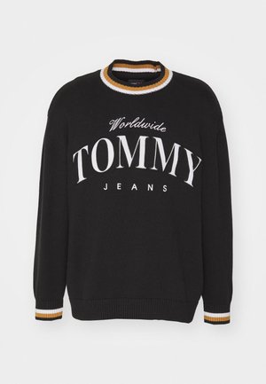 Czarny sweter z długim rękawem z białym napisem "Worldwide TOMMY JEANS" oraz prążkowanym kołnierzem i mankietami w białe i musztardowe paski.