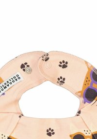 Hundetema smæk i blødt ferskenfarvet stof med poteaftryksmønstre. Det har en trykknaplukning og et mærke, der viser mærkedetaljer.