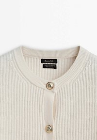 Cream-colored ribbed cardigan with a round neckline, featuring three gold-tone buttons and a label indicating wool and cashmere blend.