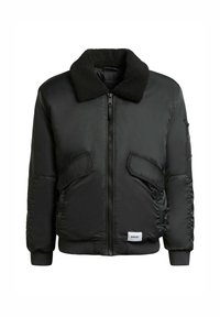 Jachetă bomber neagră cu guler pufos, fermoar în față și două buzunare laterale. Prezintă manșete și tiv cu model în valuri și un patch cu logo pe partea inferioară.