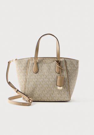 Beżowa torba typu tote Michael Kors z wzorem logo, dwoma uchwytami, odpinanym paskiem na ramię i wiszącą skórzaną metką na jednolitym tle.