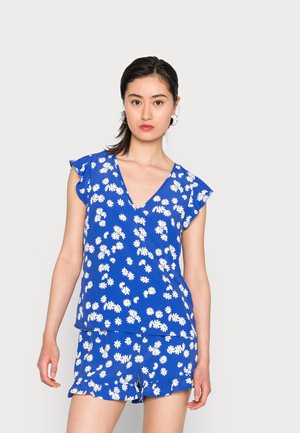 Top floral azul com decote em V e mangas tipo cava, combinado com calções iguais. Padrão branco de margaridas em tecido liso com barra de babados.