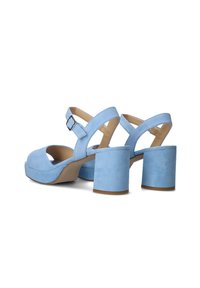 Blue suede heeled sandals with a chunky block heel, peep-toe design, and adjustable ankle strap. Smooth texture, minimalist style.