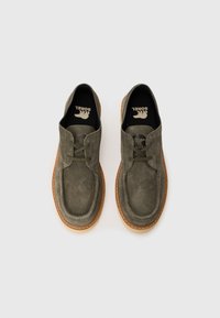 Gray suede shoes with a rounded toe, rubber outsole, and lace-up design. Features tonal stitching and a branded insole.