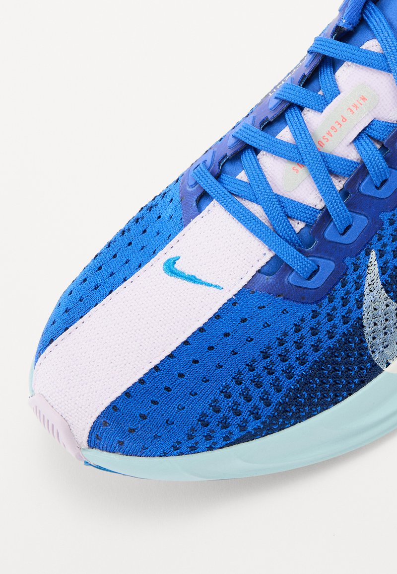 Zapatilla deportiva azul con un upper de malla transpirante, con un diseño en blanco y azul, texturas contrastantes y un logo swoosh plateado.