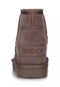 Stivali ankle in suede marrone con suola piatta, caratterizzati da accenti cuciti e un'etichetta del marchio sul retro. Design durevole e minimale.