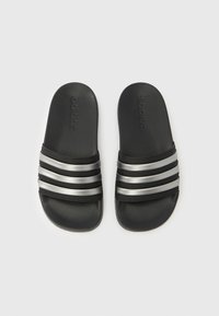 Zwarte slides met drie zilverkleurige strepen en een gestructureerd voetbed. Voorzien van een reliëflogo op het bovenwerk. Vlak ontwerp voor gemakkelijk dragen.