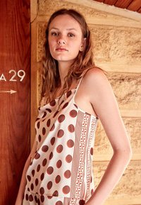 Haut sans manches marron à pois avec un design drapé, comportant un panneau rayé contrastant. Confectionné en tissu léger à la texture lisse.