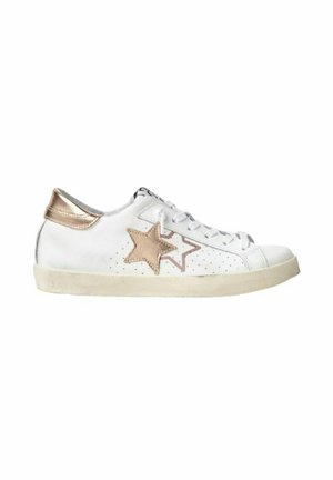 Sneaker bianca bassa con stelle beige sul lato e linguetta posteriore beige, con lacci bianchi e suola leggermente usurata.