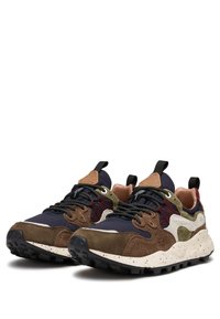 Scarpe da atletica multicolori con un mix di tessuto blu navy, suede marrone e dettagli verdi, dotate di una suola intermedia bianca macchiata e una suola esterna in gomma nera.