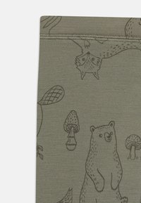 Grüner Stoff mit tier- und naturbezogenen Illustrationen in Braun, darunter ein Bär, ein Fuchs, Pilze und Blätter, mit einer strukturierten Oberfläche.