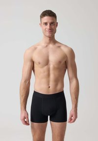Boxer in cotone neri con una vestibilità aderente, caratterizzati da un elastico semplice. Il tessuto appare liscio e elastico, progettato per comfort e supporto.