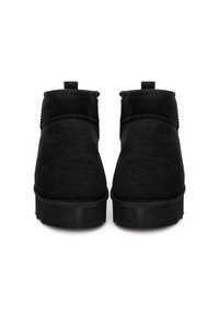 Botines negros de ante con una textura suave, con puntera redondeada, de altura corta y suela plana. Sin acentos de hardware visibles.