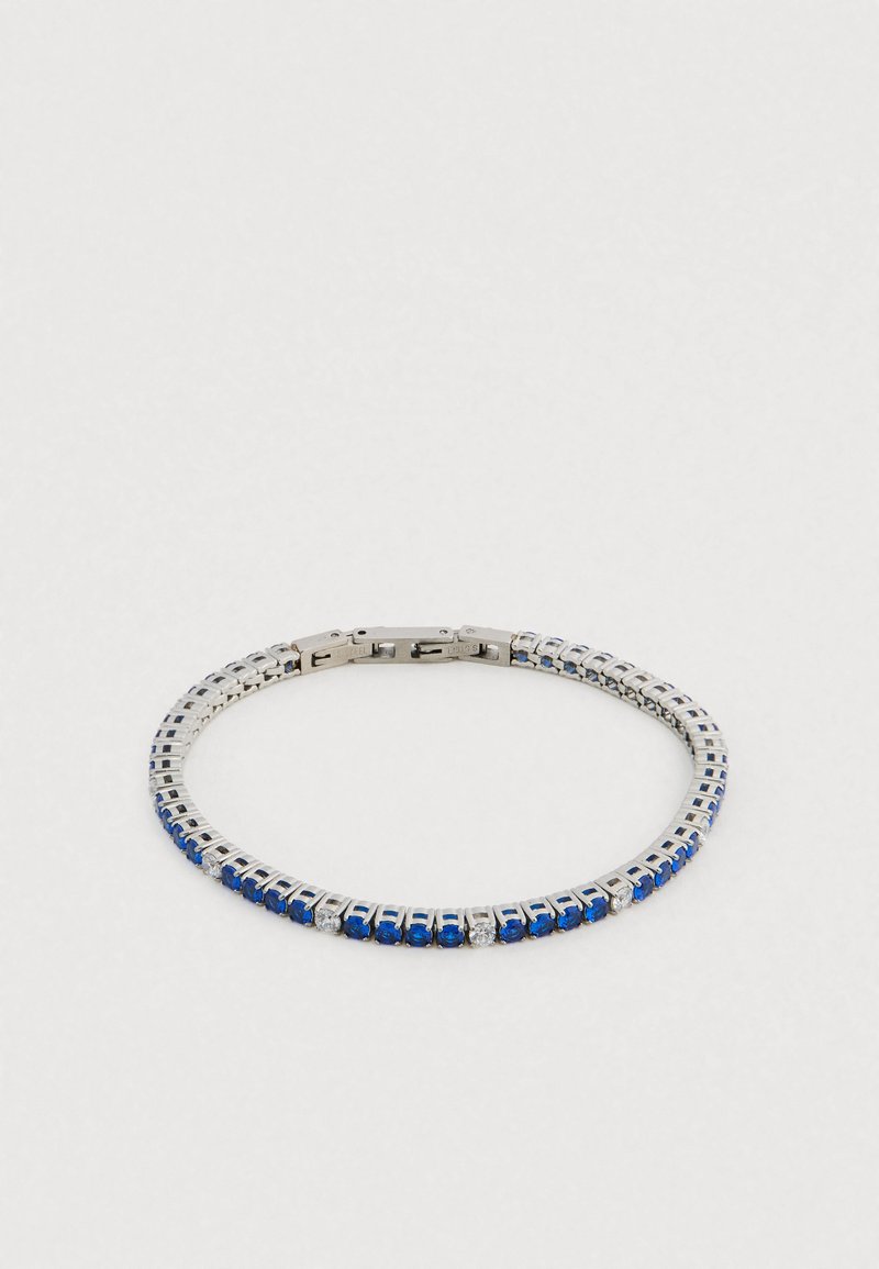 Srebrna bransoletka z niebieskimi i przezroczystymi kryształami, o elastycznym designie i zapięciu na klamrę. Gładka metalowa tekstura z prostokątnym wzorem.