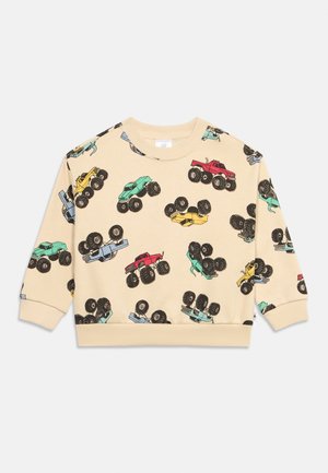 Bluză bej cu mânecă lungă, cu ilustrații colorate de camioane monstru în roșu, galben, verde și albastru, împrăștiate pe întreaga țesătură.