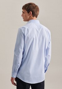  Lichtblauw geruit overhemd met lange mouwen, zachte stof en klassieke kraag. Voorzien van knoopmanchetten en rugplooien voor bewegingsvrijheid.