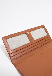 Cartera de cuero marrón con dos secciones transparentes para tarjetas y múltiples ranuras para tarjetas. Acabado texturizado y detalle de cierre a presión dorado.