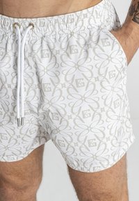 Bijele kupaće gaće s ponavljajućim svijetlosivim cvjetnim uzorkom s logotipom. Elastična waistband s vezicom i bočnim džepovima.