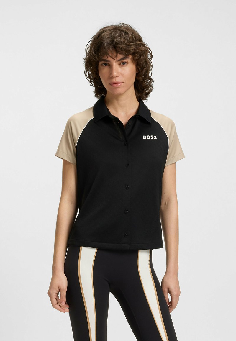 Svart kortärmad polo med beige axlar, framknappar och "BOSS"-logotyp. Mjuk tygkvalitet med en skräddarsydd passform.