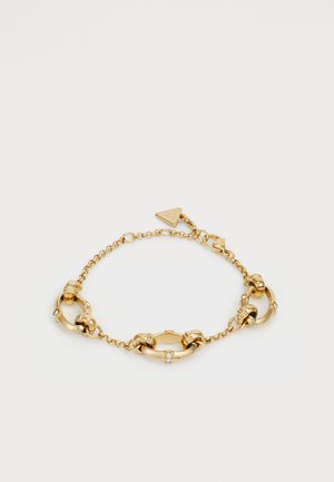 Bracelet en chaîne dorée avec des maillons ronds entrelacés, de petits accents ronds et un fermoir en tag triangulaire. Texture lisse et brillante sur l'ensemble.