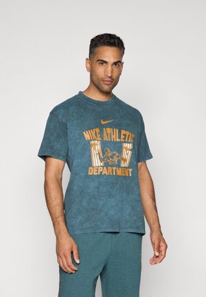 Mikset af bomuld, mørk teal crew neck t-shirt med orange "Nike Athletic Department" grafik. Korte ærmer, afslappet pasform, subtil tie-dye tekstur.