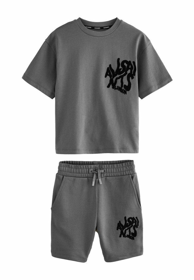 Camiseta de algodón gris de manga corta y shorts a juego, con un logo negro texturizado en el pecho izquierdo y el muslo, y cintura elástica.