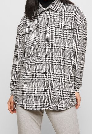 Long-sleeve, black and white checkered shirt with button closures and two chest pockets. Made of a textured fabric with a relaxed fit.