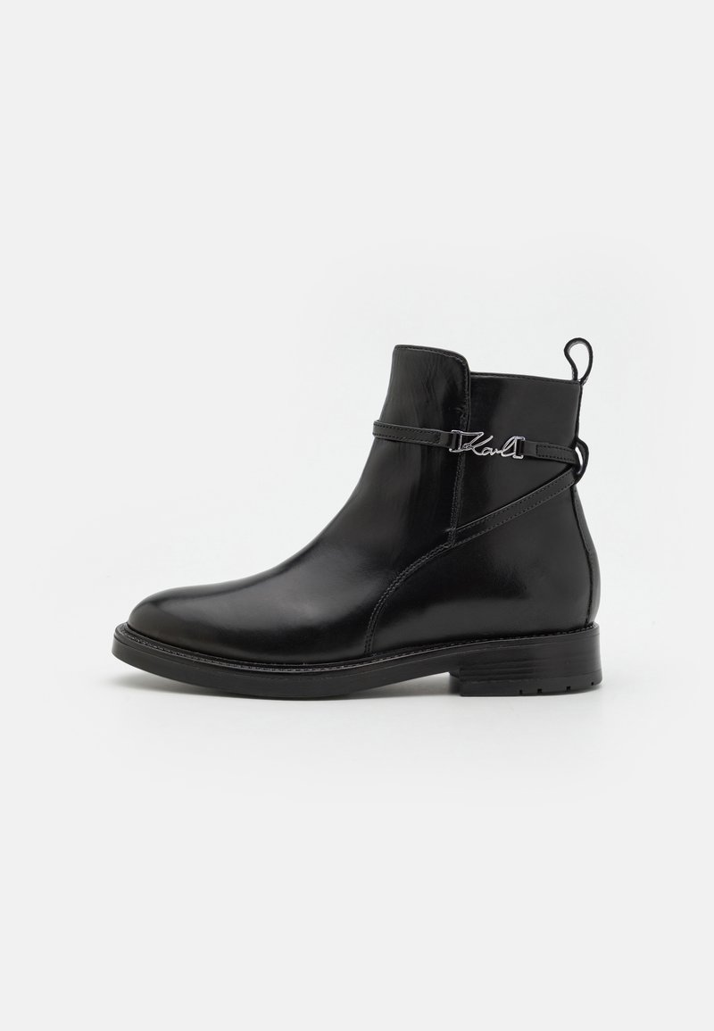 Black leather ankle boot with a rounded toe, decorative strap with logo, and a low block heel. Smooth texture and minimalist design.