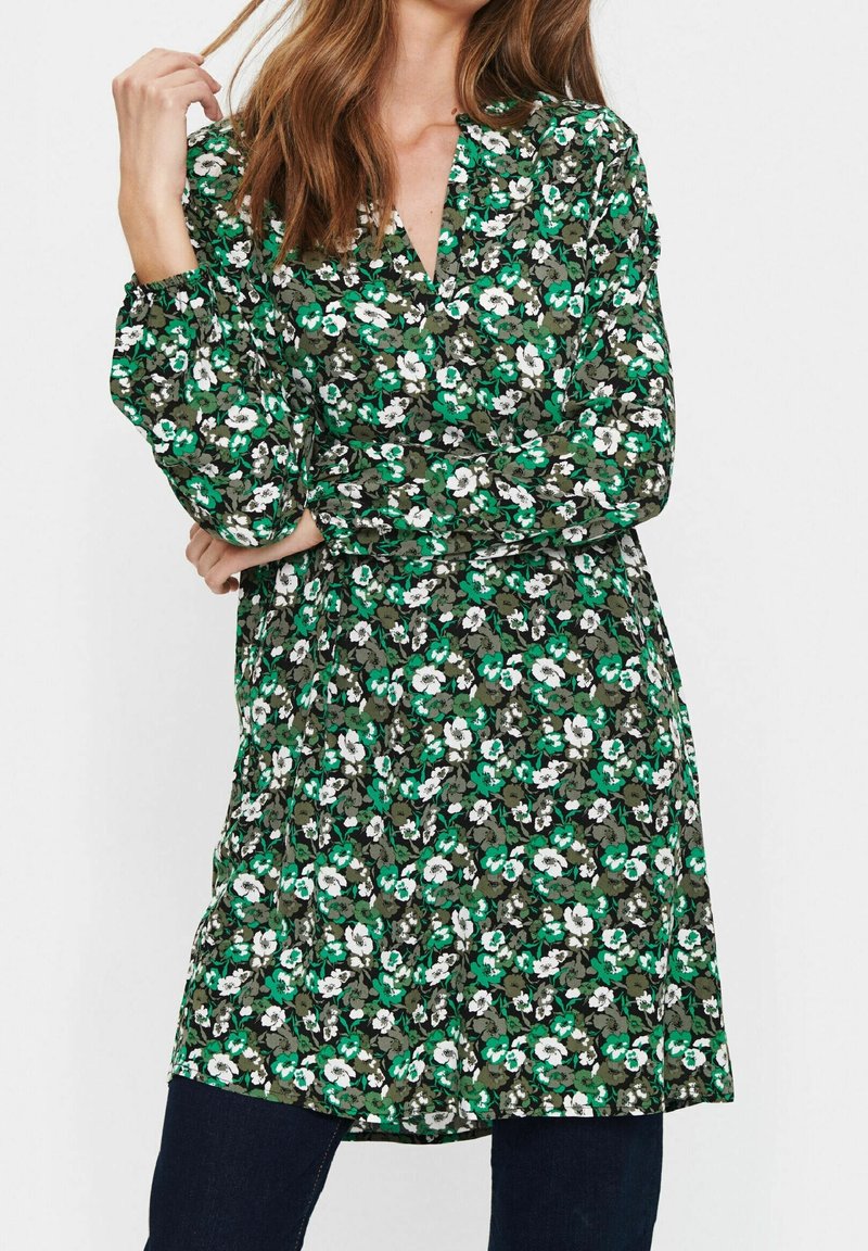 Robe fleurie en tissu vert, blanc et gris. Encolure en V, manches longues et coupe ample. Présente un motif de petites fleurs.