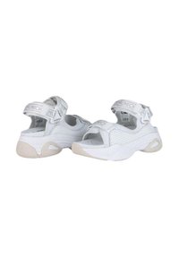 Sandalias deportivas blancas con un diseño de malla transpirable, correas ajustables de velcro y una suela de goma texturizada con un acento en beige claro.